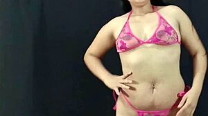 若くて曲線美のあるラテン系美女がピンクのランジェリーでアセットを誇示し、ホットな写真撮影の準備をします。