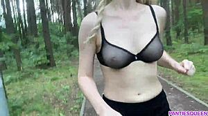 Une femme blonde fait de l'exercice en plein air dans le parc, exposant son corps nu et ses seins rebondissants